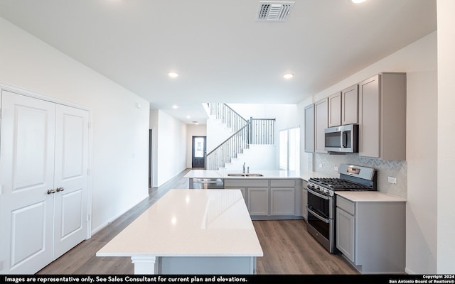 kitchen featuring gray cabinetry, kitchen peninsula, stainless steel appliances, hardwood / wood-style flooring, and sink