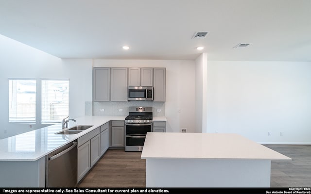 kitchen with wood-type flooring, kitchen peninsula, sink, and stainless steel appliances