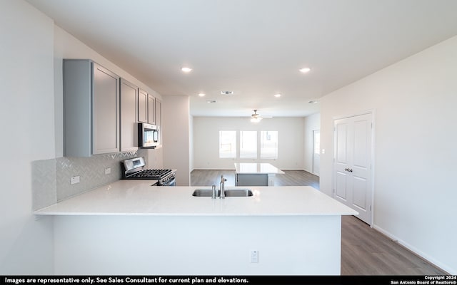 kitchen with sink, stainless steel appliances, dark hardwood / wood-style floors, and kitchen peninsula