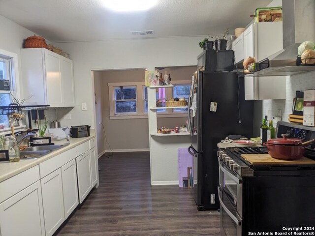 kitchen featuring sink, range with two ovens, wall chimney exhaust hood, and white cabinetry