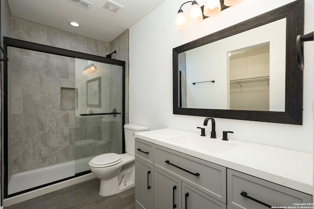 bathroom with vanity, hardwood / wood-style flooring, toilet, and an enclosed shower