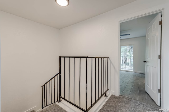 stairs with ceiling fan and carpet