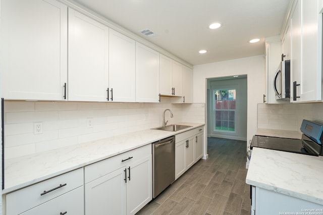 kitchen with light stone counters, white cabinets, sink, hardwood / wood-style flooring, and stainless steel appliances