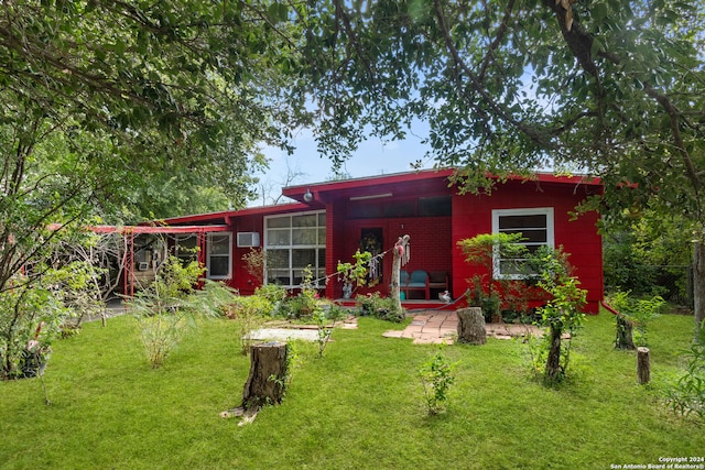 back of property with a lawn, a wall mounted AC, and a patio area