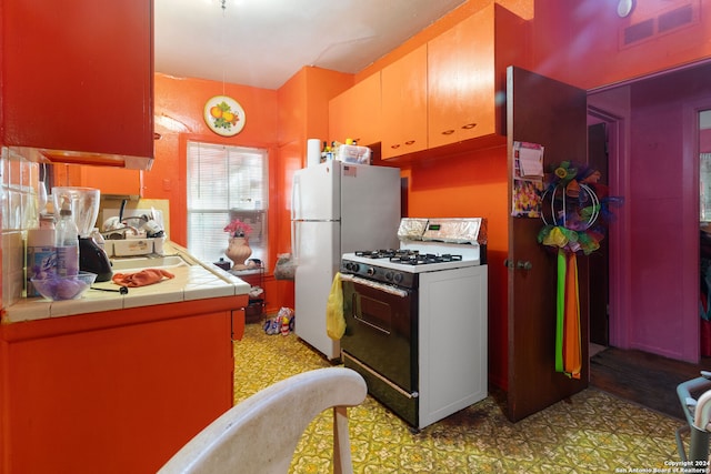 kitchen featuring white appliances, sink, and tile countertops