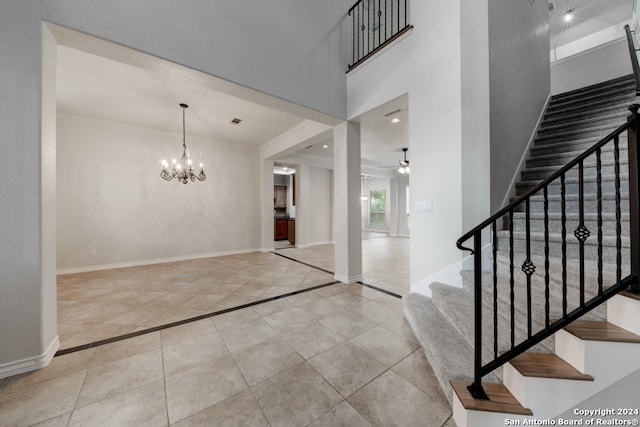 tiled foyer entrance with ceiling fan with notable chandelier