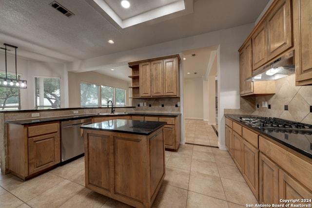 kitchen with appliances with stainless steel finishes, decorative backsplash, hanging light fixtures, a center island, and sink