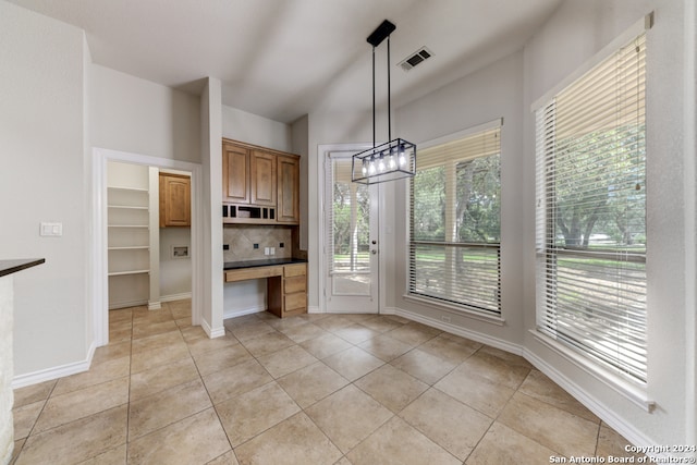 kitchen featuring backsplash, light tile patterned floors, and decorative light fixtures