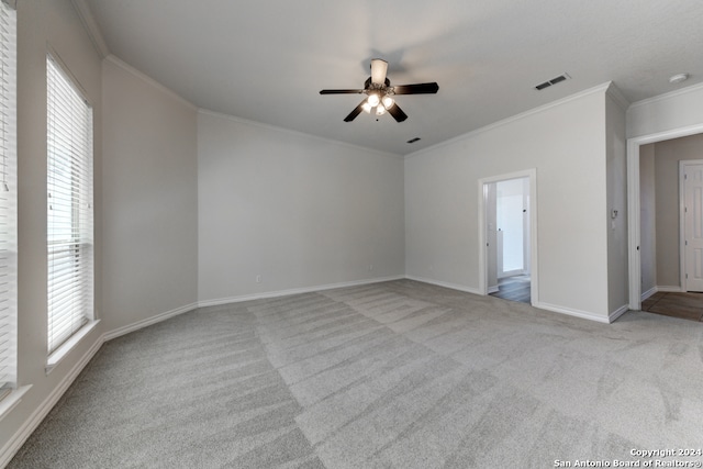 empty room featuring ceiling fan, light carpet, and crown molding