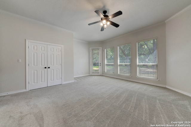 interior space with a textured ceiling, crown molding, ceiling fan, and light colored carpet