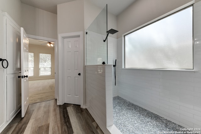 bathroom with wood-type flooring, ceiling fan, and tiled shower