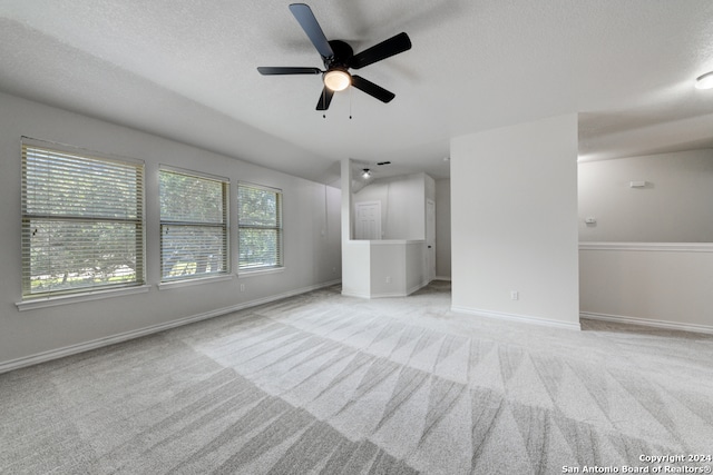 unfurnished living room with a textured ceiling, lofted ceiling, light carpet, and ceiling fan