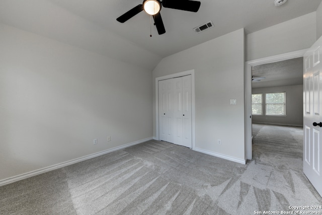 unfurnished bedroom featuring lofted ceiling, light carpet, ceiling fan, and a closet