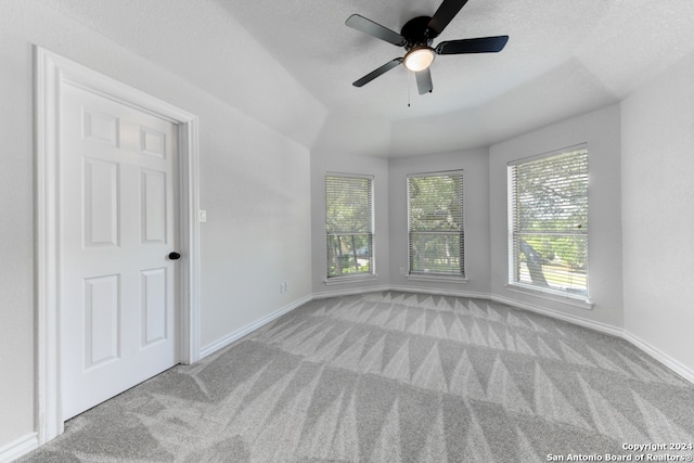 carpeted empty room featuring lofted ceiling, ceiling fan, and a textured ceiling