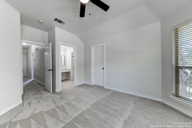 unfurnished bedroom featuring connected bathroom, lofted ceiling, ceiling fan, and light colored carpet