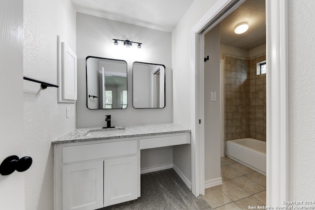 bathroom with tile patterned flooring, tiled shower / bath, and vanity