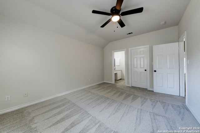 unfurnished bedroom with vaulted ceiling, ensuite bath, ceiling fan, and light colored carpet