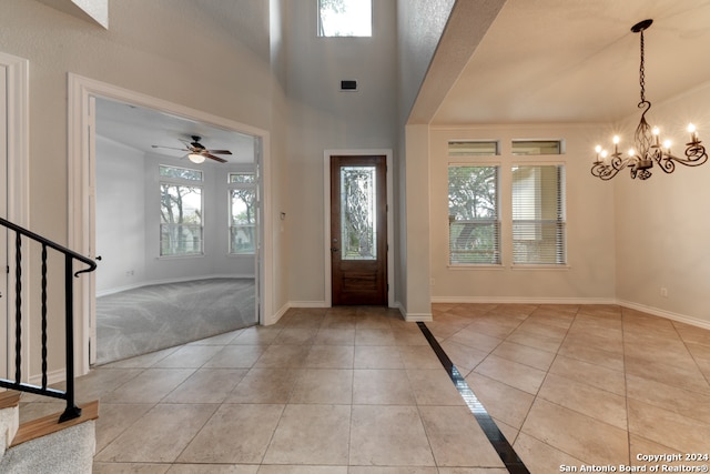 tiled entrance foyer featuring ceiling fan with notable chandelier