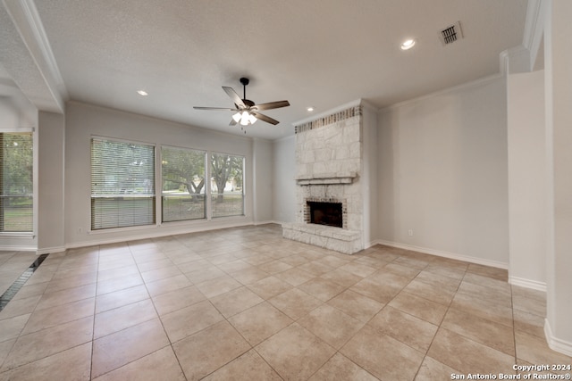 unfurnished living room featuring ceiling fan, light tile patterned flooring, a textured ceiling, a fireplace, and crown molding