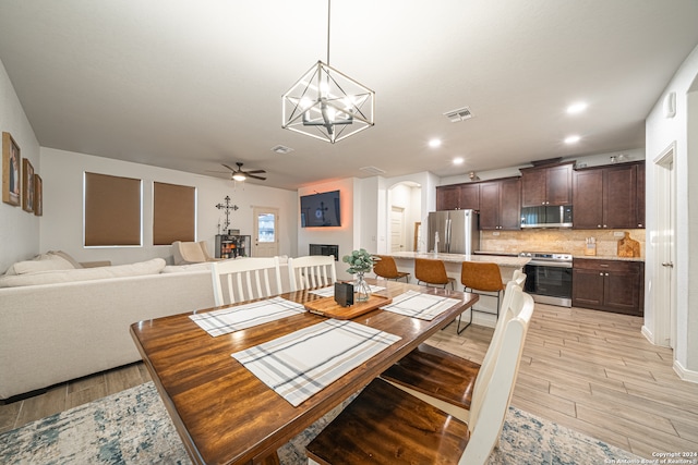 dining space featuring ceiling fan with notable chandelier and light wood-type flooring