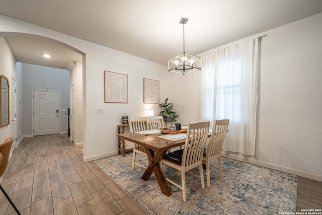 dining area with wood-type flooring and a notable chandelier