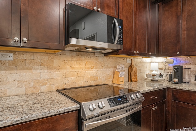 kitchen with backsplash, stainless steel appliances, and light stone counters