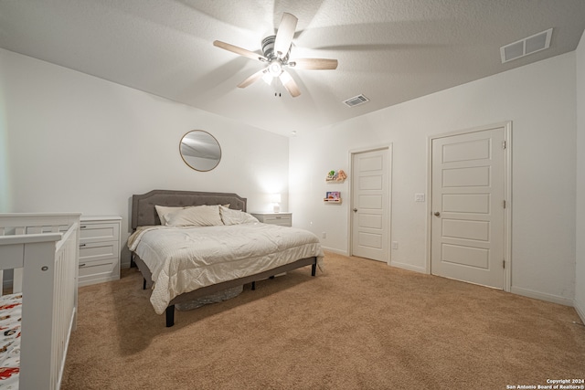 bedroom featuring a textured ceiling, ceiling fan, and light colored carpet