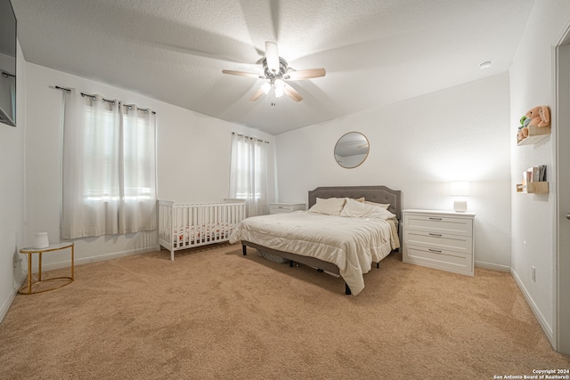 bedroom with vaulted ceiling, ceiling fan, light colored carpet, and a textured ceiling