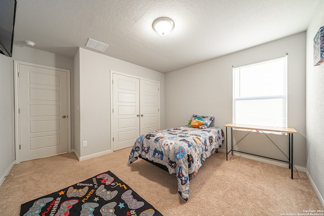 carpeted bedroom featuring a closet and a textured ceiling