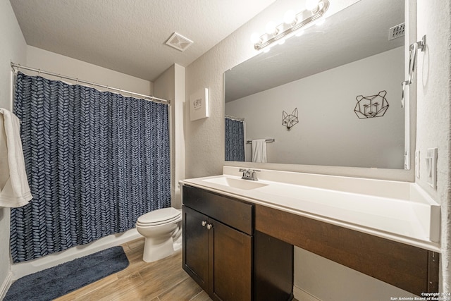 bathroom featuring vanity, a textured ceiling, hardwood / wood-style floors, walk in shower, and toilet