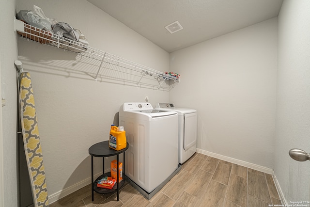 clothes washing area featuring light hardwood / wood-style floors and washer and dryer