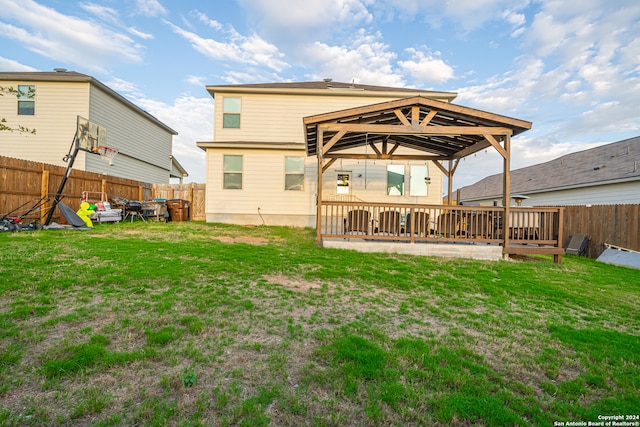 back of house featuring a lawn and a wooden deck