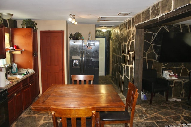 kitchen featuring a stone fireplace, black range oven, fridge with ice dispenser, and sink