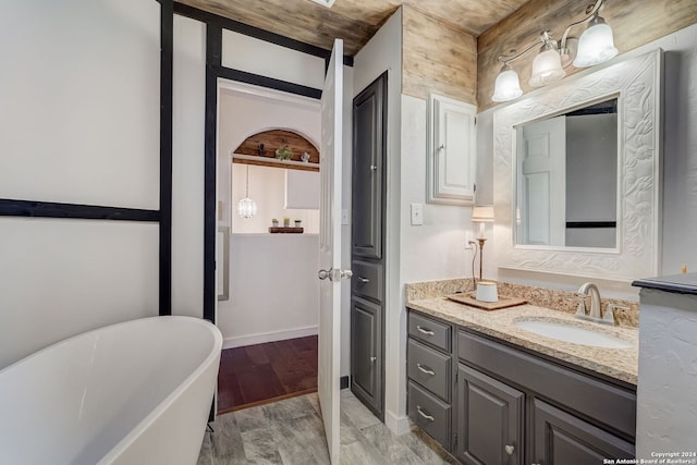 bathroom featuring wood-type flooring, wooden ceiling, a washtub, and vanity