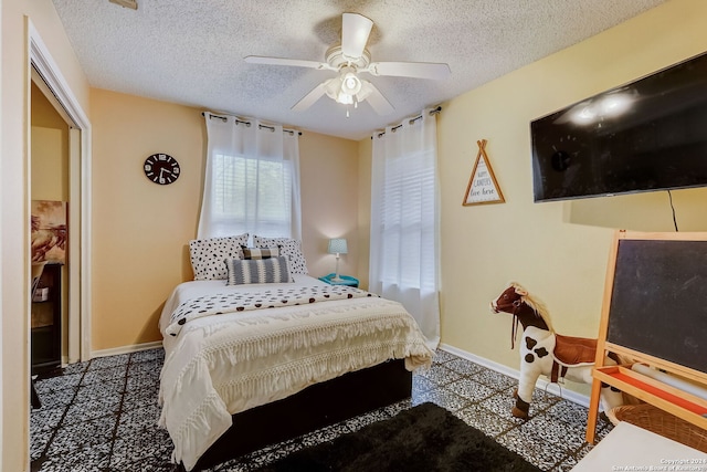 bedroom with ceiling fan and a textured ceiling