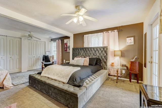 bedroom featuring ceiling fan, two closets, and multiple windows