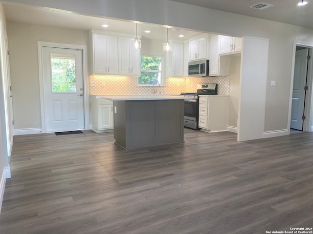 kitchen with a kitchen island, dark wood-type flooring, pendant lighting, white cabinetry, and appliances with stainless steel finishes