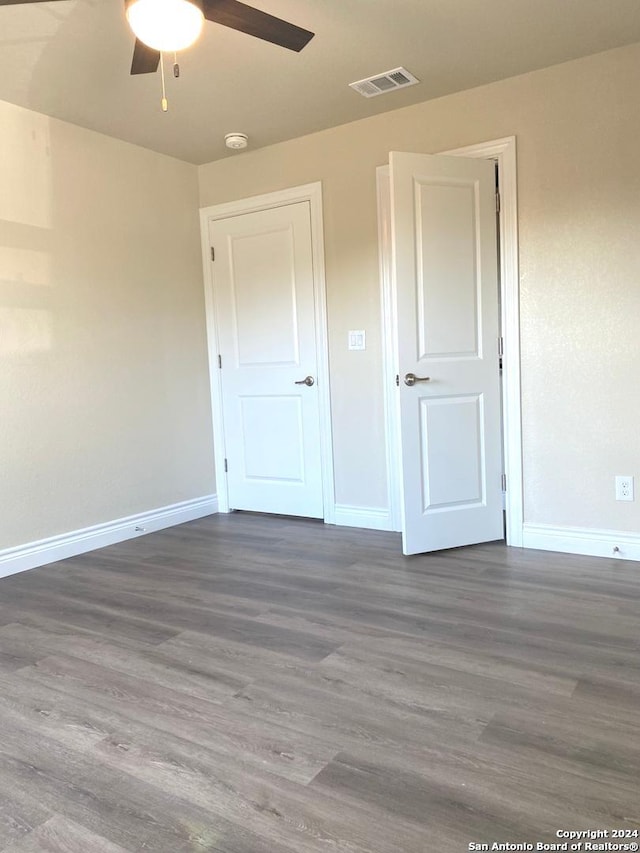 unfurnished bedroom featuring dark wood-type flooring and ceiling fan