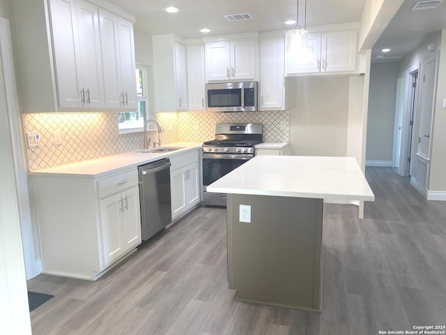 kitchen featuring white cabinets, appliances with stainless steel finishes, sink, pendant lighting, and a center island