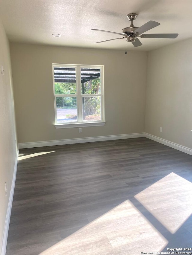 spare room with a textured ceiling, dark hardwood / wood-style floors, and ceiling fan