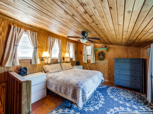 bedroom featuring ceiling fan, wood walls, dark tile patterned floors, and wooden ceiling