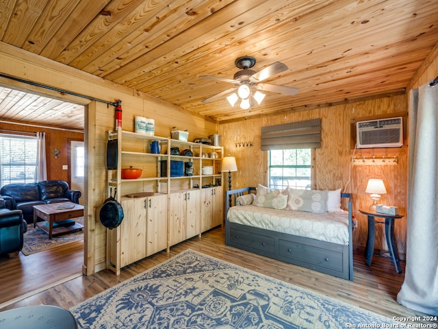 bedroom featuring wooden walls, light hardwood / wood-style flooring, multiple windows, and an AC wall unit