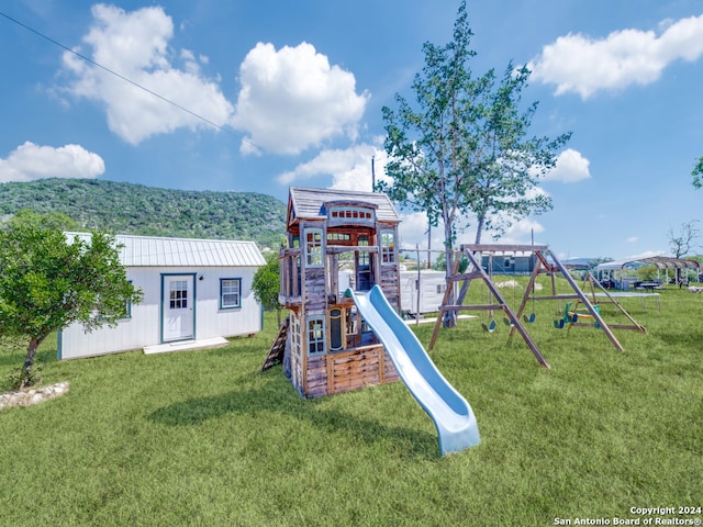 view of playground featuring a lawn and a mountain view