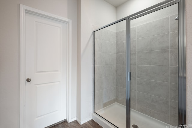 bathroom featuring a shower with shower door and hardwood / wood-style floors