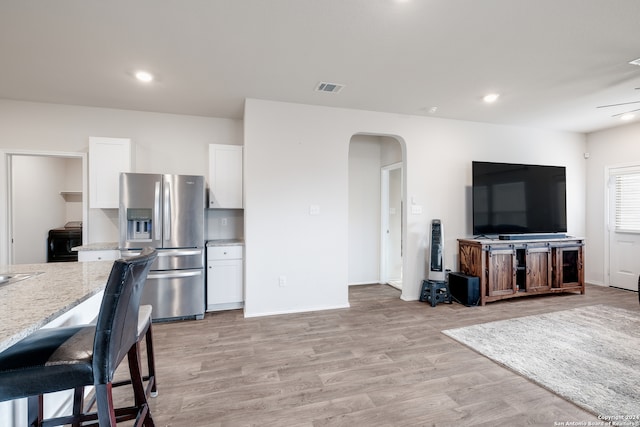 interior space featuring light hardwood / wood-style flooring, white cabinetry, light stone counters, and stainless steel fridge