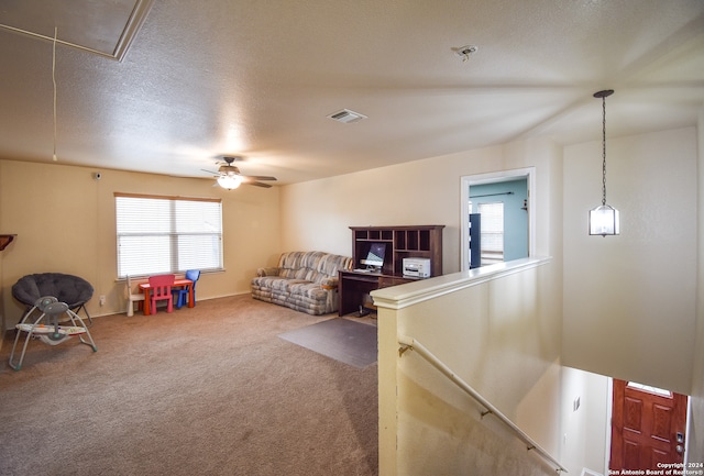 sitting room with ceiling fan, carpet floors, and a textured ceiling