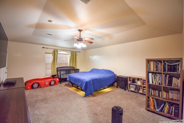 bedroom featuring ceiling fan, a raised ceiling, and carpet