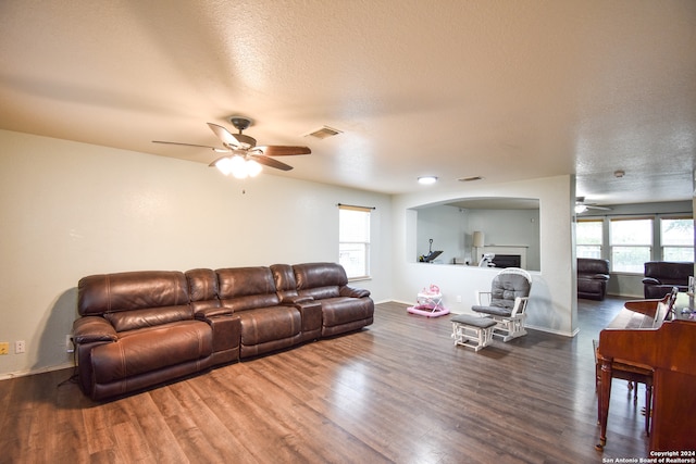 living room featuring ceiling fan, a textured ceiling, and dark hardwood / wood-style floors