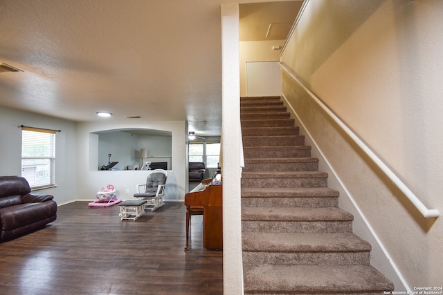 stairs with ceiling fan, hardwood / wood-style floors, and a textured ceiling