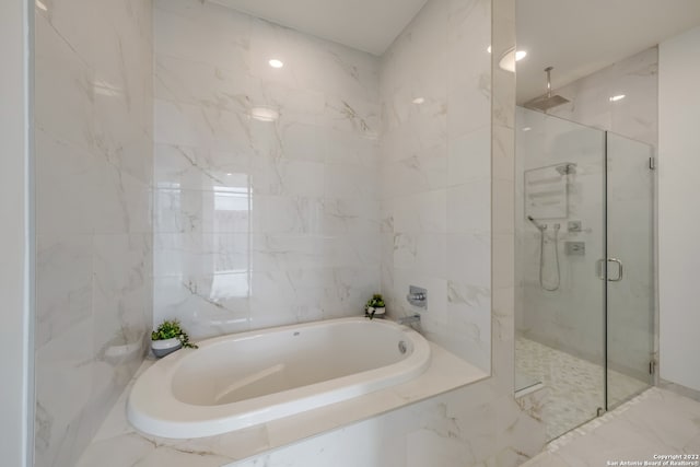 bathroom featuring plus walk in shower and tile walls